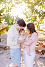 A family is holding a baby on a beach in miami.