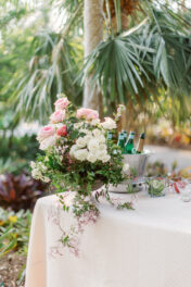 A table with flowers and a bottle of wine on it.