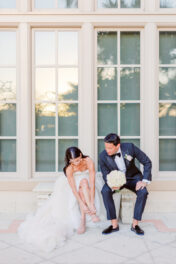 A bride and groom sitting on the steps of a building.